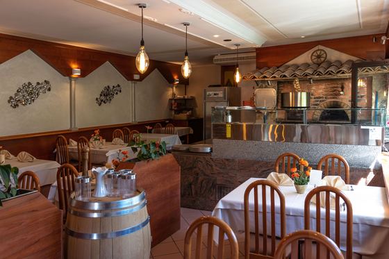 Gastraum mit gedeckten Tischen und traditionellem Pizzaofen
